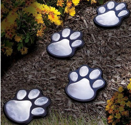 Creative Vault Marketplace solar-powered black plastic bear paw garden lights arranged on mulch near yellow flowers.