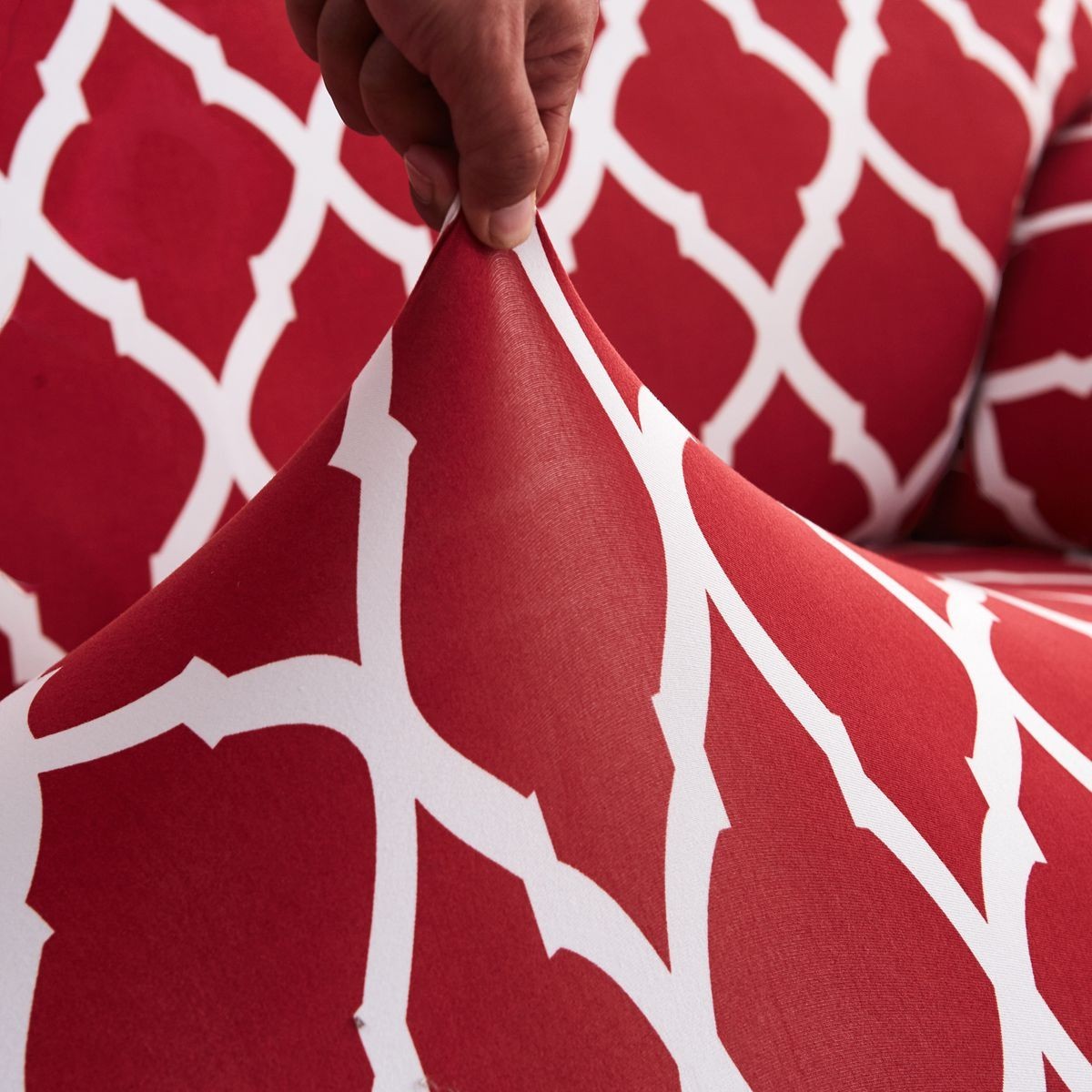 Creative Vault Marketplace red and white floral pattern elastic sofa cover fabric being stretched by a hand